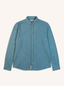 A long sleeve men's shirt in a textured cotton fabric, dyed in light blue.