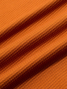 A waffle textured cotton material in orange, used to make the KESTIN Fly Tee.