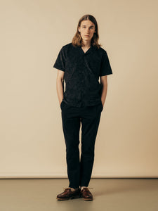 A model wearing a pair of slim fit black trousers and a short sleeve shirt.