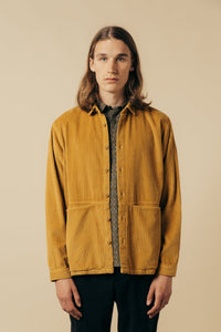 A model wearing a casual overshirt/jacket in a light brown corduroy.