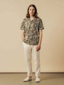A man wearing a casual spring outfit from KESTIN, with white trousers and a green shirt.