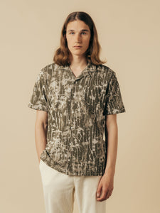 A man wearing a short sleeve shirt with a casual camo design.