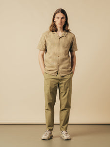 A model wearing a short sleeve shirt with a beige check pattern.