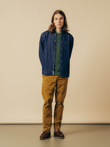 A model wearing a denim shirt, striped t-shirt and slim fit trousers from KESTIN.