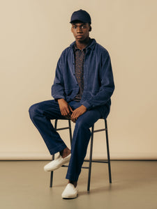 A tonal blue men's outfit, worn by a model who is sitting down.