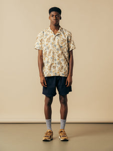 A model wearing a pair of navy blue shorts and a short sleeve floral shirt from menswear brand KESTIN.