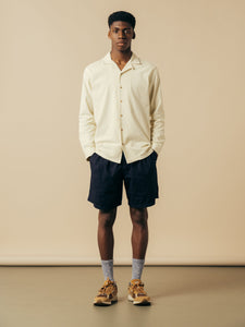 A model wearing a pair of navy blue shorts and a white shirt from KESTIN.