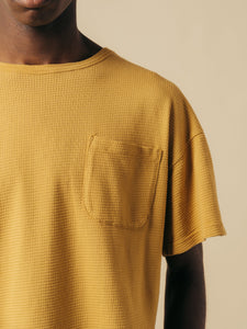 A close-up of the shoulder and chest pocket from the KESTIN Fly Tee in yellow.