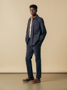 A man wearing a navy blue jacket with slim fit trousers, from menswear brand KESTIN.
