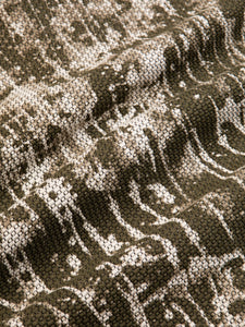 A woven cotton fabric with a modern camo-splattered design in green and white.