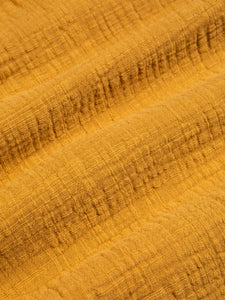A textured cotton material, garment dyed in a rich yellow colour.
