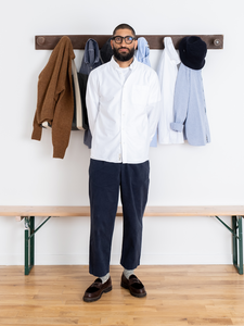 A man wearing a smart-casual outfit, consisting of relaxed fit Chinos, leather shoes and a classic white Oxford Shirt, designed by British menswear brand KESTIN.